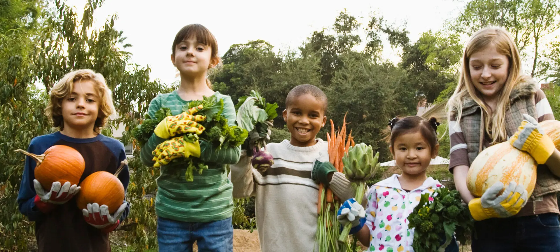 kinderen met pompoen, artisjok, wortels en bladgroente